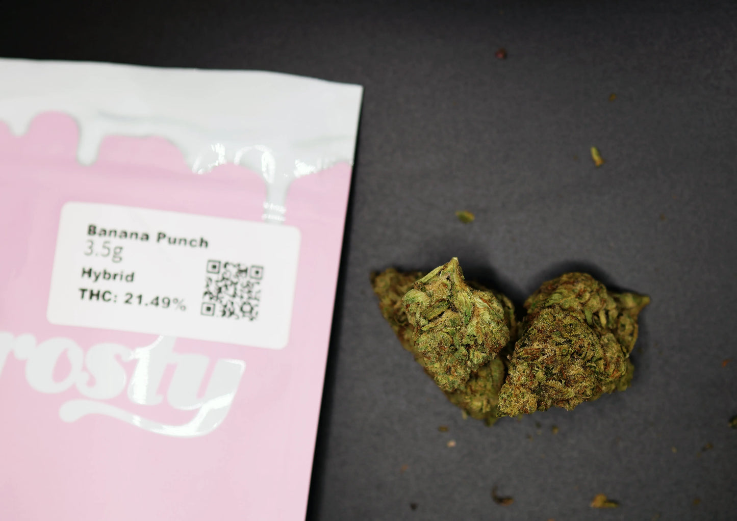 Pink packaging of 'Banana Punch' with cannabis buds on a dark surface