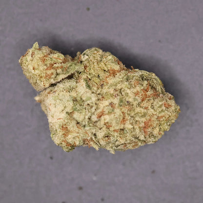 Close-up of a clump of columbian gold thca flower on a gray background
