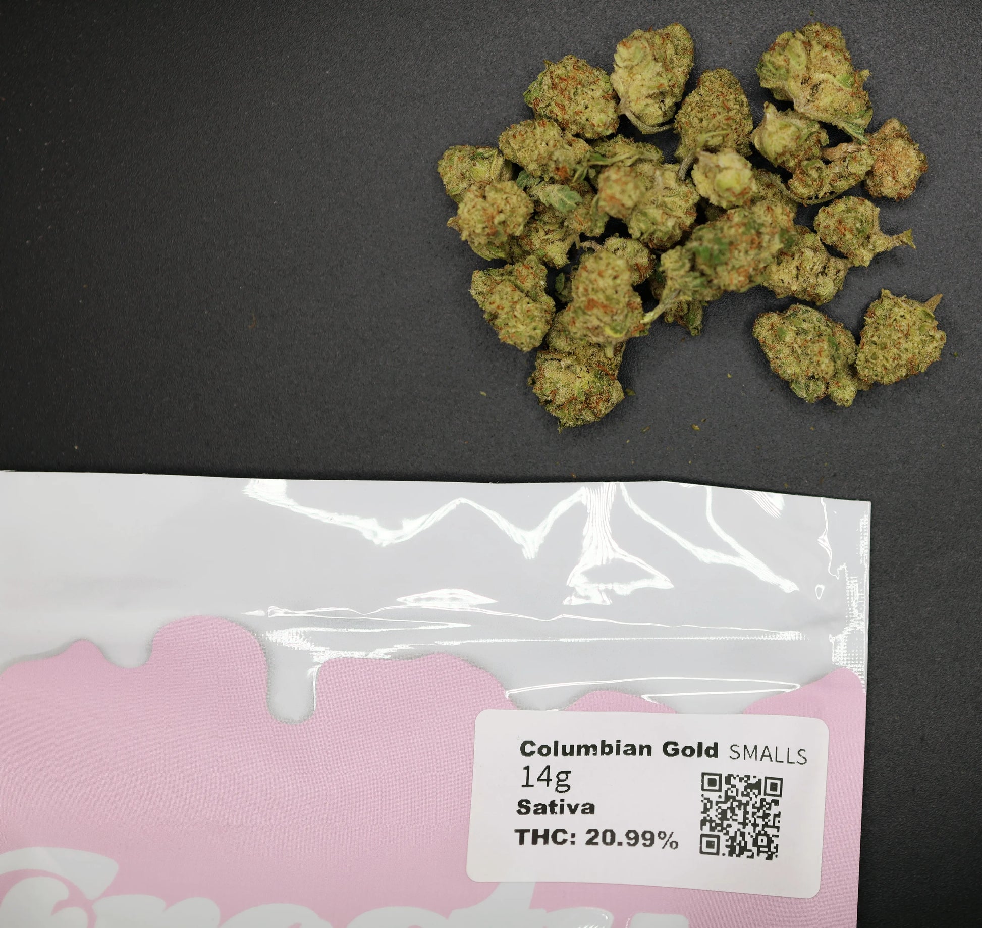 smalls columbian gold buds on a black surface with a pink packaging label displaying product details.