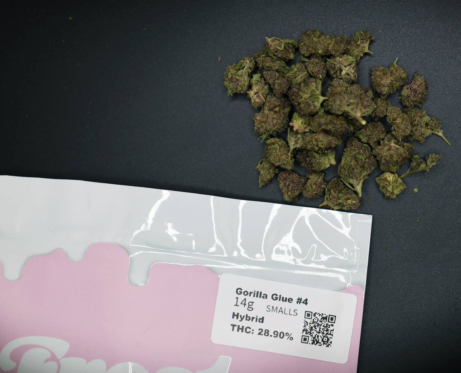 Dried cannabis buds with a Gorilla Glue product label on a dark surface