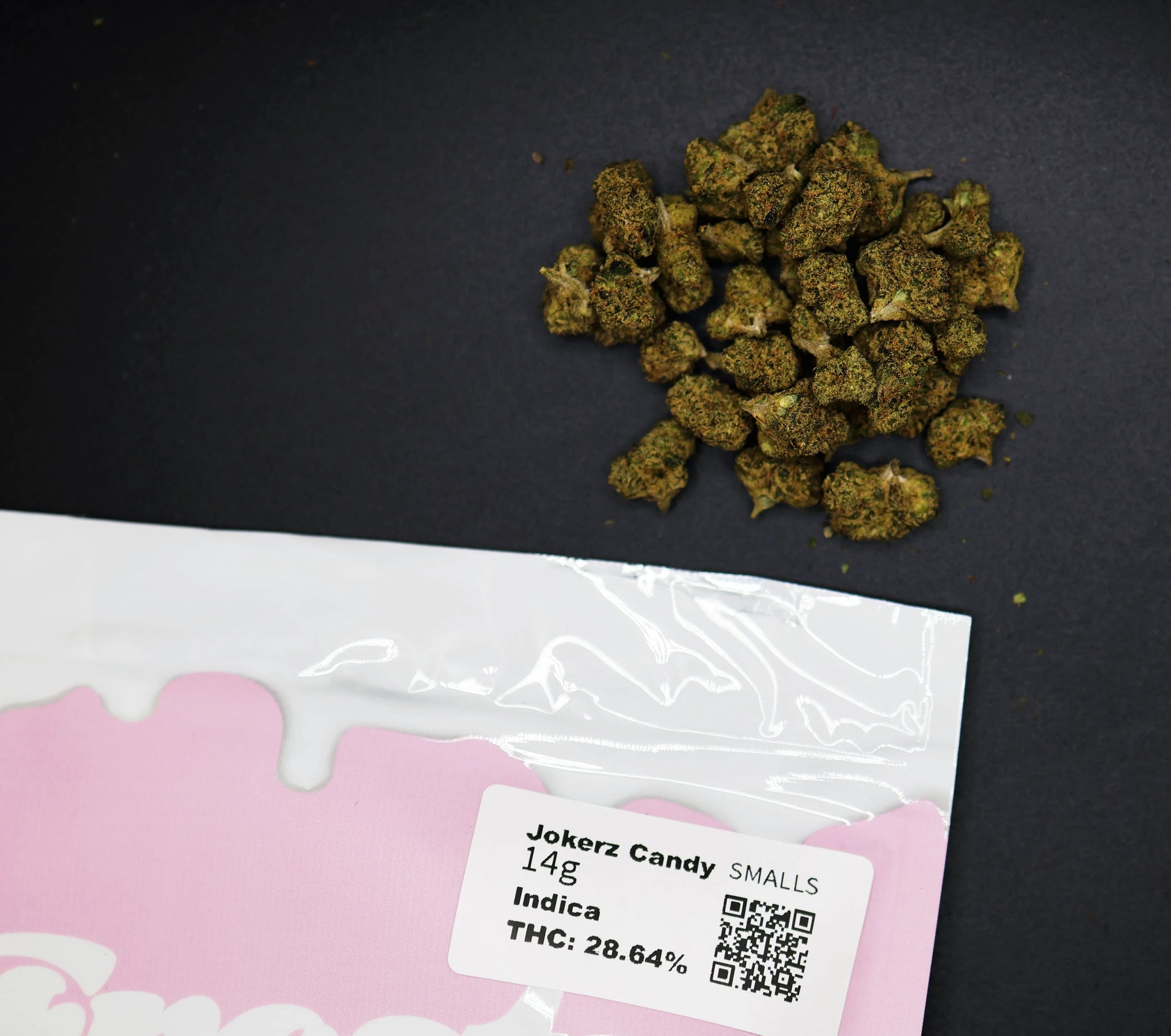 Cannabis buds on a black surface with a pink packaging label for jokerz candy smalls buds 