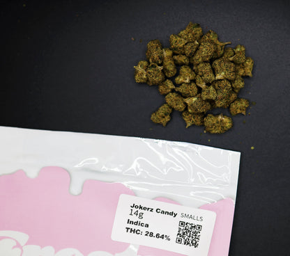 Cannabis buds on a black surface with a pink packaging label for jokerz candy smalls buds 
