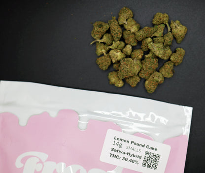 Marijuana buds on a black surface with a pink packaging label for 'Lemon Pound Cake' strain.
