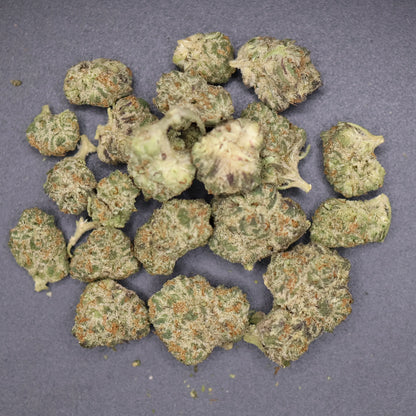 pile of northern lights smalls buds on a flat dark surface showing detail of high thca content 