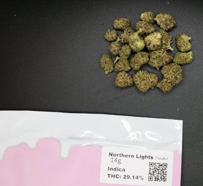 Marijuana buds on a dark surface with a 'Northern Lights' packaging label.