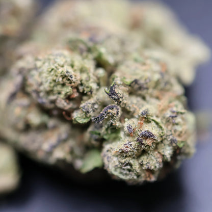 Close-up of a pistachio runtz cannabis bud with green and brown colors on a dark background