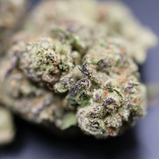 Close-up of a pistachio runtz cannabis bud with green and brown colors on a dark background
