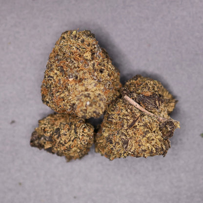 Close-up of dried space pop thca buds on a gray background